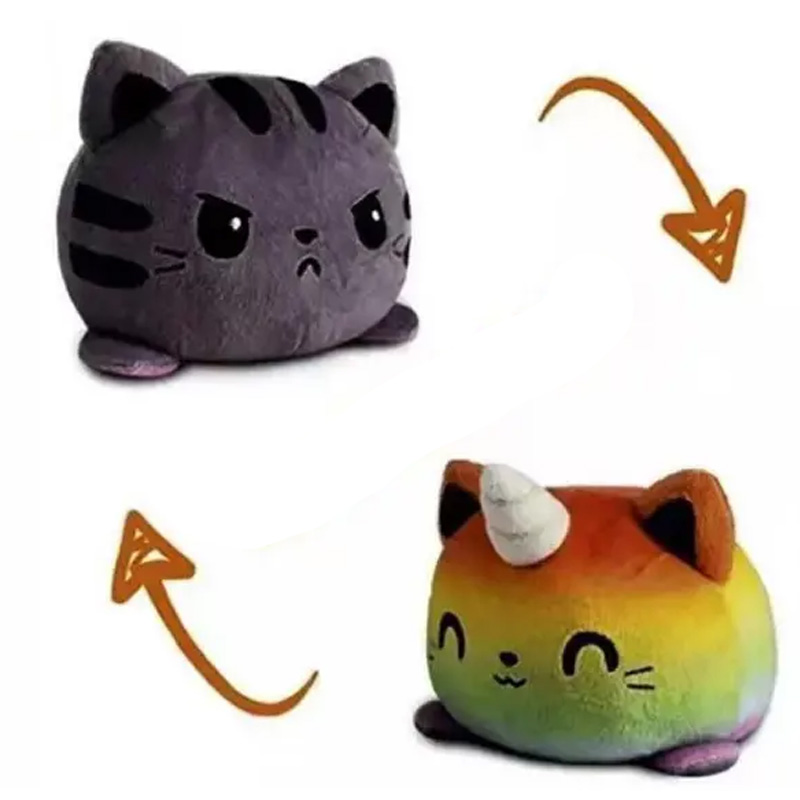 Zwei Ansichten eines Katzen-Wende-Plüschtiers. Auf einer Seite ist es regenbogenfarben, hat ein Horn auf der Stirn und schaut glücklich, auf der anderen Seite ist es schwarz und schaut grimmig.