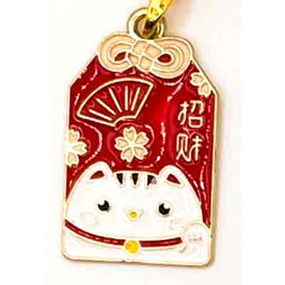 Goldener Anhänger in Form eines japanischen Geschenkanhängers. Darauf ist eine weiße winkende Katze auf rotem Hintergrund abgebildet.
