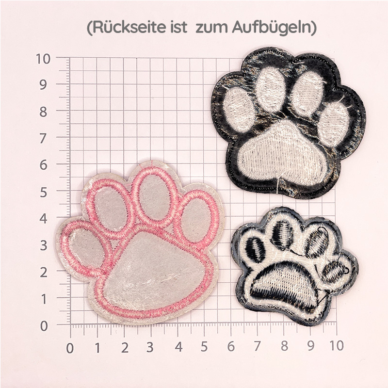 Rückansicht von 3 Aufnähern in Tierpfotenform in den Farben schwarz-weiß, weiß-schwarz oder rosa.