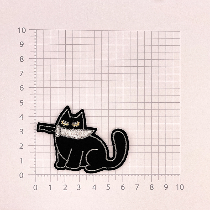 Aufnäher in Form einer Katze mit schwarzem Fell, die ein Messer im Mund hält.