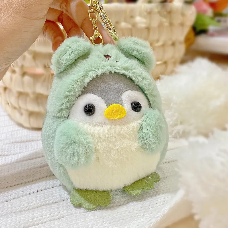 Plüschpinguine-Schlüsselanhänger in grünem Bärenkostüm.