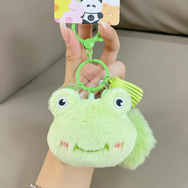 Ein grüner plüschiger Schlüsselanhänger in Froschkopfform.