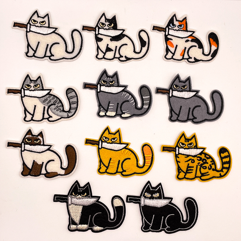 11 Aufnäher in Form von Katze mit unterschiedlichen Fellfarben, die ein Messer im Mund halten.