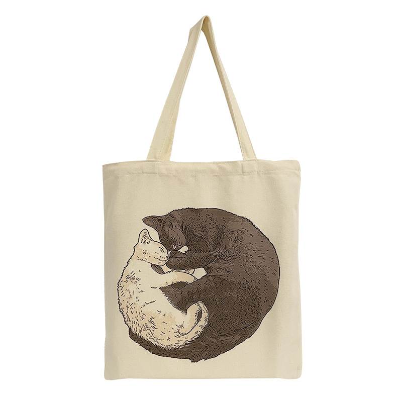 ES-22-001-2 Baumwolltasche mit dem Motiv einer weißen und einer schwarzen Katze, die zusammen kuschelnd auf dem Boden liegen und aussehen wie das Yin & Yang Zeichen.