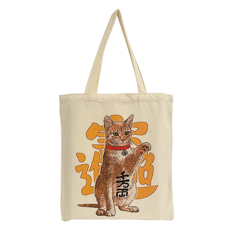 ES-22-001-1 Baumwolltasche mit dem Motiv einer sitzenden orange-weißen Katze, die eine Pfote anhebt. Hinter ihr und auf ihrem Bauch sind asiatische Schriftzeichen abgebildet.